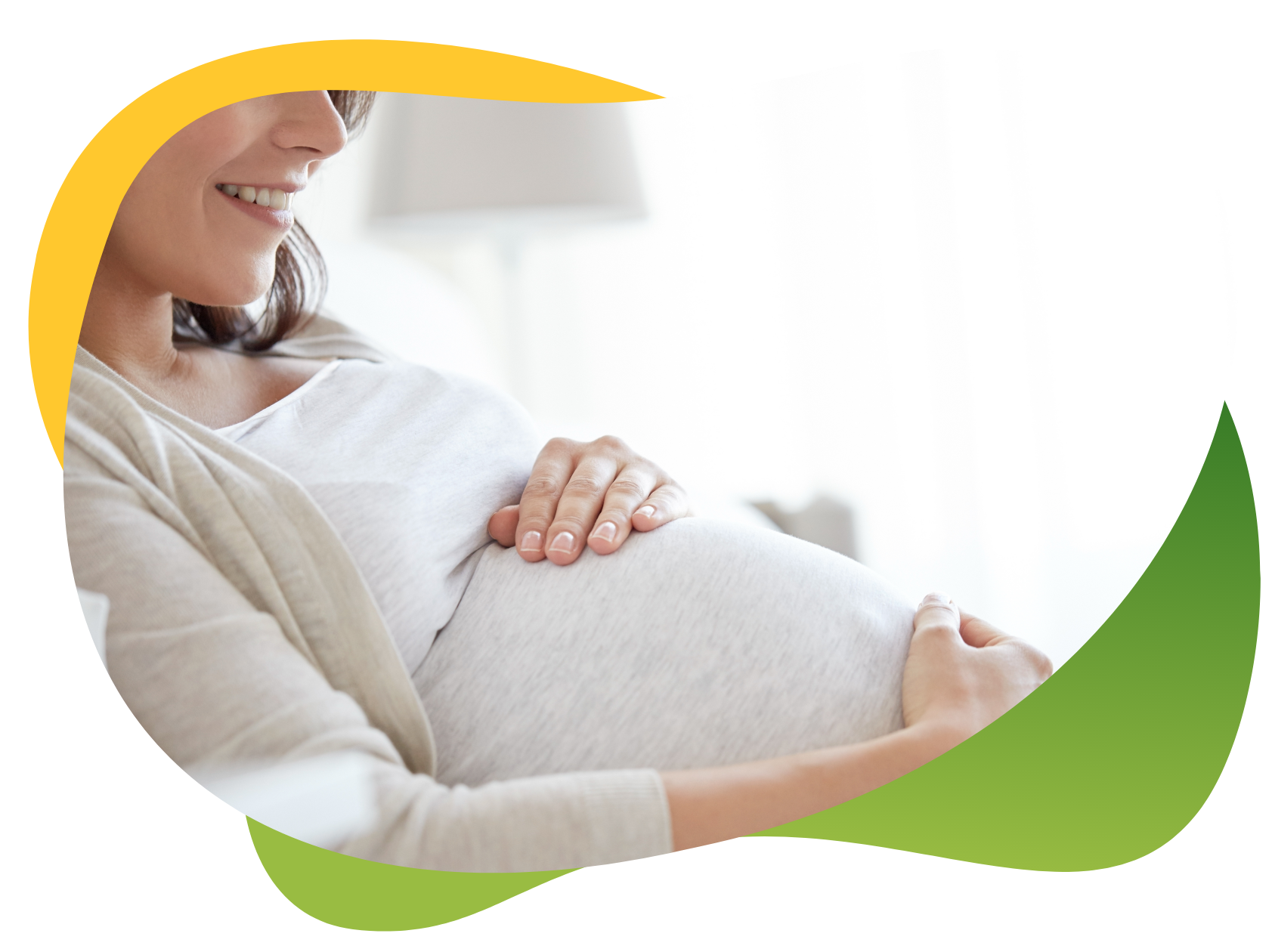 Těhotná žena, kterou netrápí nadýmání, sedí a usmívá se a přitom si hladí těhotné bříško.