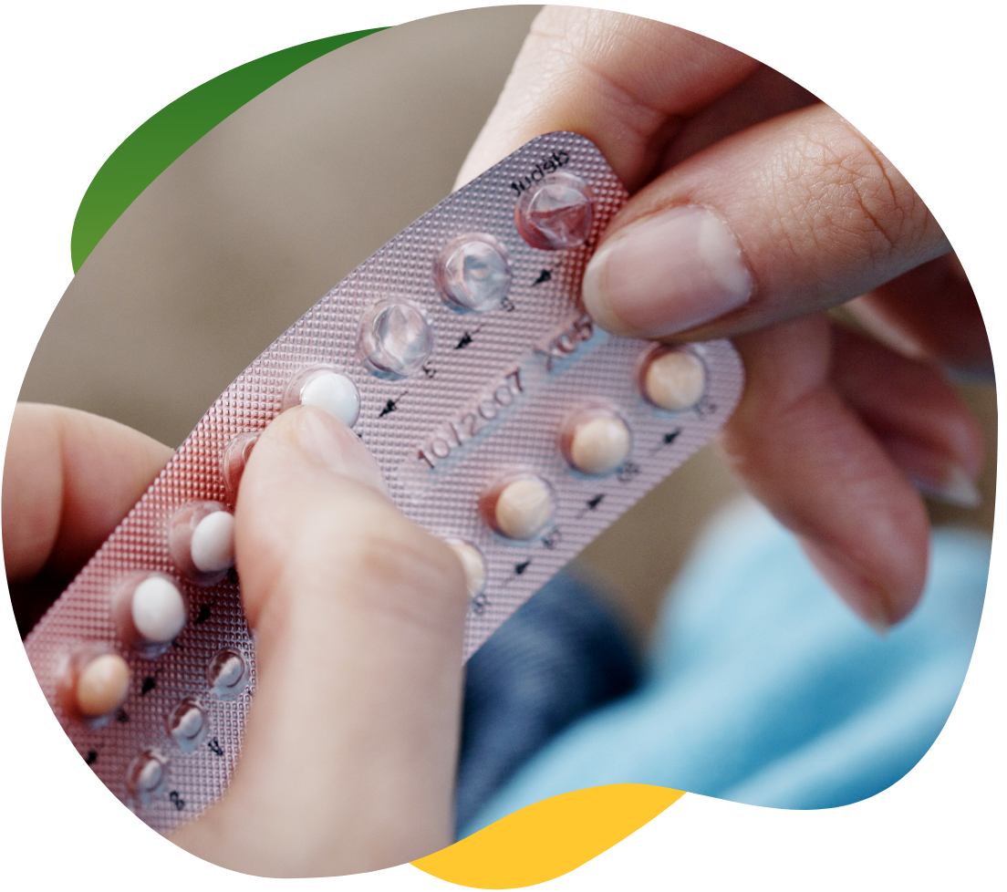 Ruka ženy, která z balení vymačkává antikoncepční pilulku.